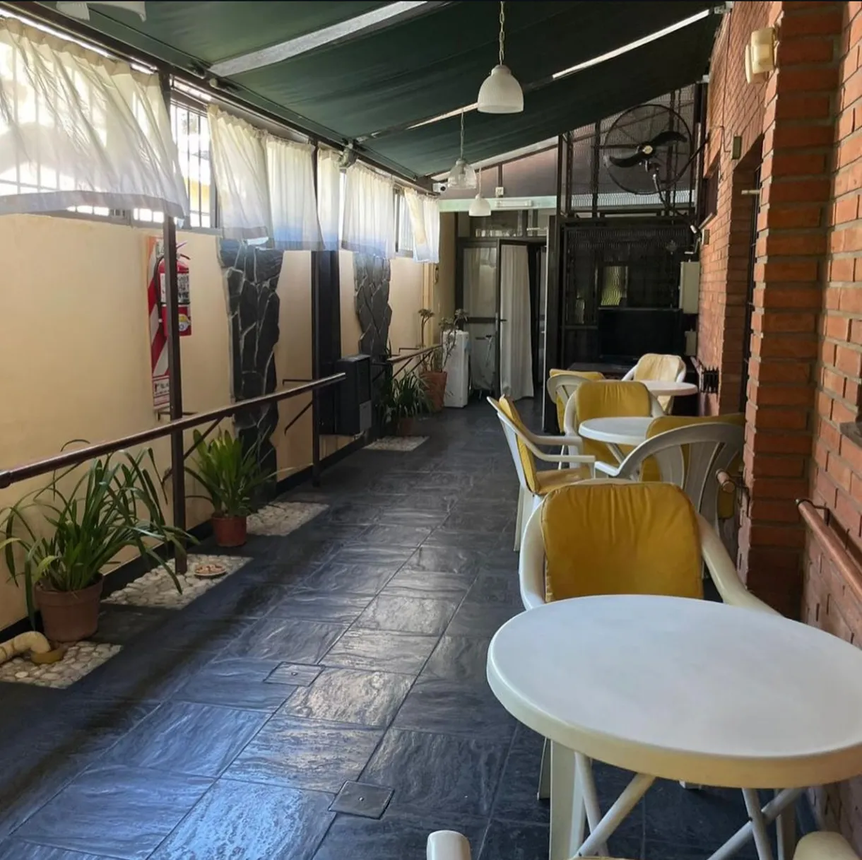 Galería cubierta con mesas, sillas y plantas de Casa San Juan