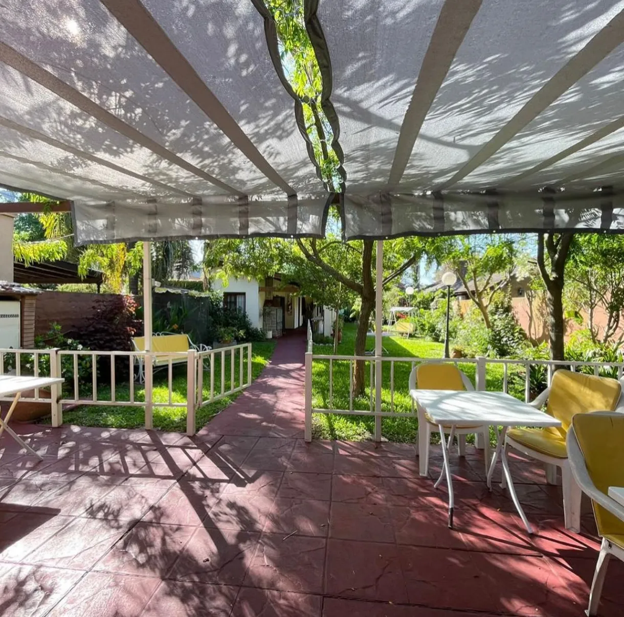 Galería semicubierta con mesas junto al jardín de Casa San Juan